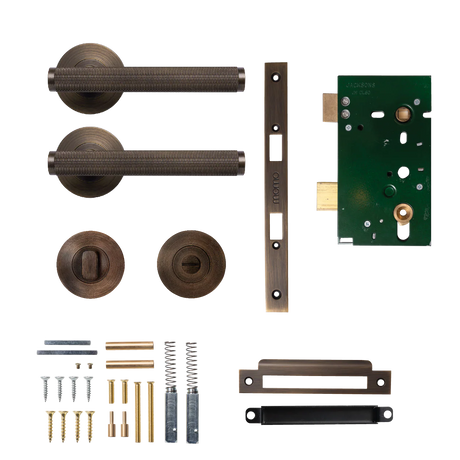 Collection of bronze door handles and lock components on a white background. BellevueSolidBrassKnurledMorticeLockPrivacyLeverSetInBronze