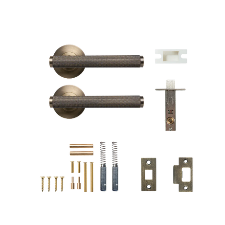 Door handle set with components on a white background. BellevueSolidBrassKnurledTubularLatchPassageLeverSetInDarkBrushedBrass
