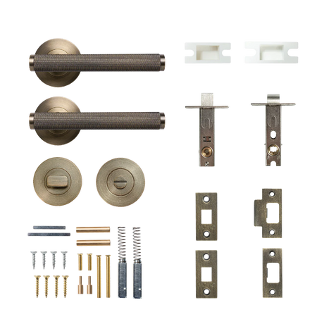 Collection of door hardware components on a white background. BellevueSolidBrassKnurledTubularLatchPrivacyLeverSetInDarkBrushedBrass
